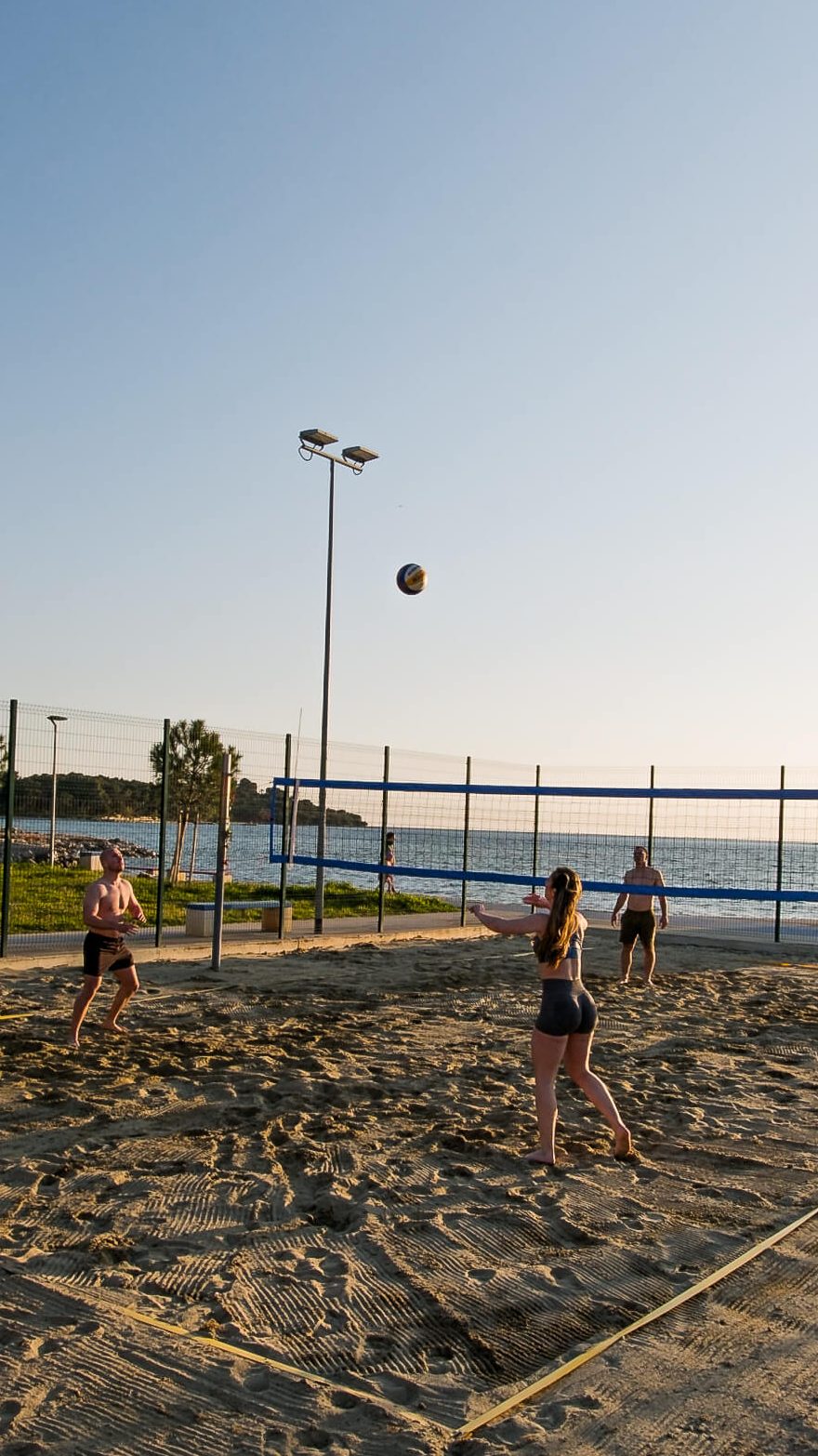 Lampuga Fitness Camp participants playing volleyball in the sunset